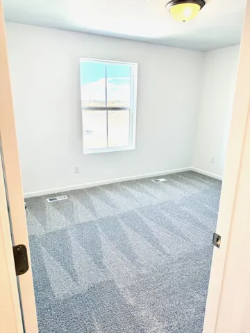 Bedroom #2. White walls, recessed window, gray carpet, and flush mount ceiling light