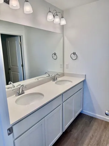 Secondary bath across from the laundry room with separate room for the tub and toilet. Double vanity with undermount sinks, chrome fixtures, and light-toned countertop