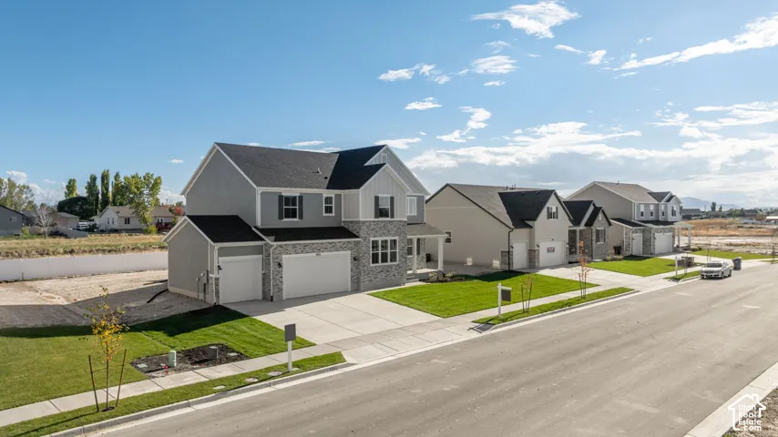Two-story residence featuring a gray exterior with stone veneer accents, a multi-gabled roofline, and a three-car attached garage
