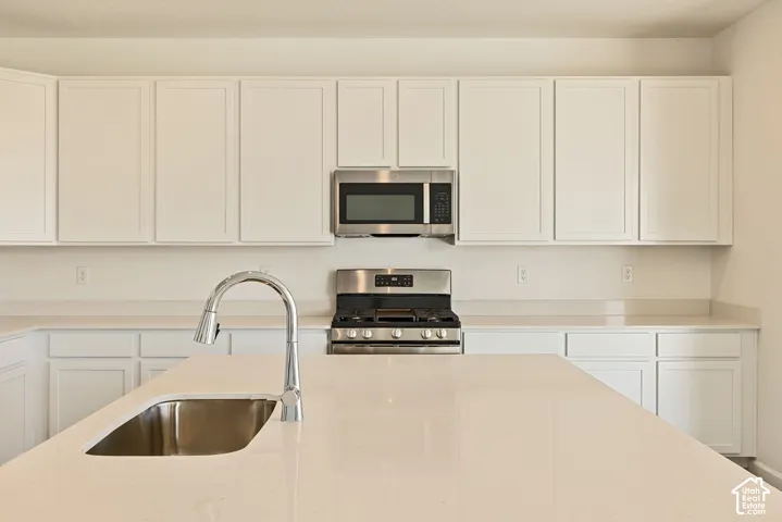 Plenty of Cupboards and countertop space, with quartz countertops, and stainless-steel appliances including a gas range, and a center island with a large single bowl undermount sink.