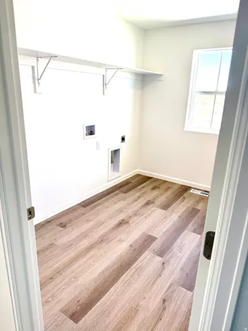 Utility room with wood-finish flooring, a window, and built-in shelving