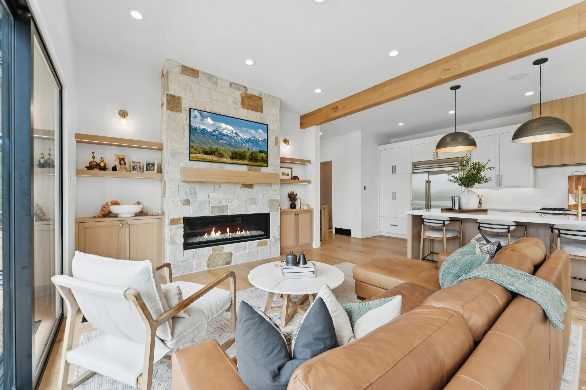 Open-concept living area featuring a stone-clad fireplace with a linear firebox, natural wood-finish mantel, and integrated built-in cabinetry with open shelving