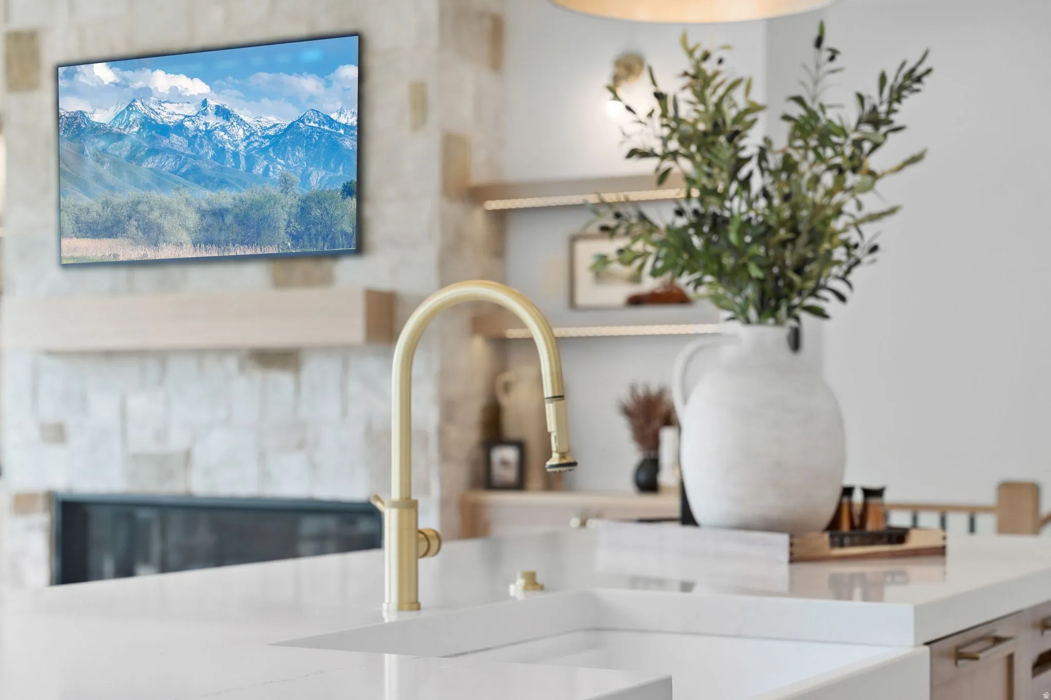 Contemporary kitchen island featuring a white countertop with an integrated sink and a gold-tone faucet