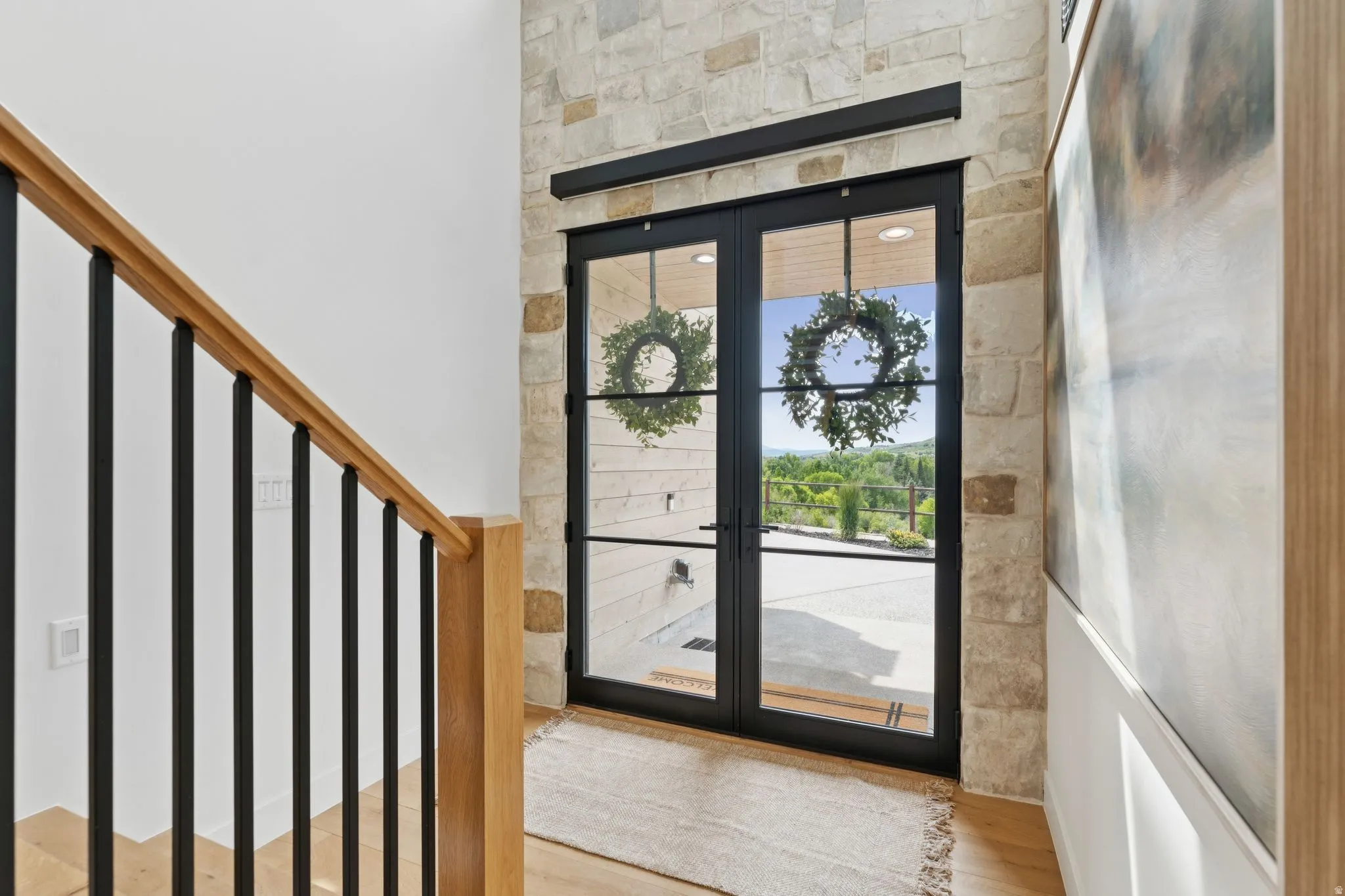 Double black-framed glass entry doors with transom, set within a natural stone wall