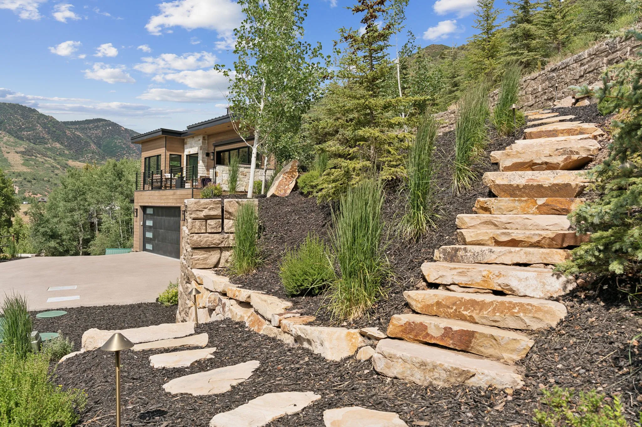 Terraced landscaping featuring natural stone steps and retaining walls, complemented by varied evergreen and deciduous plantings