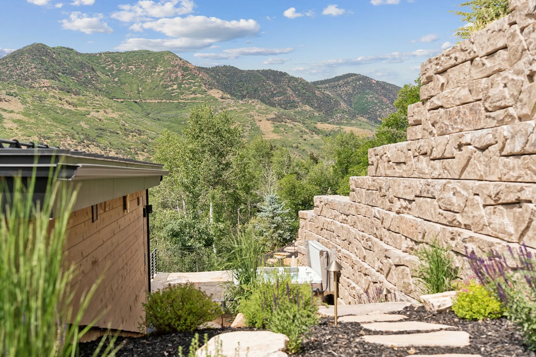 Tiered stone retaining walls define the landscape, featuring integrated lighting and diverse plantings