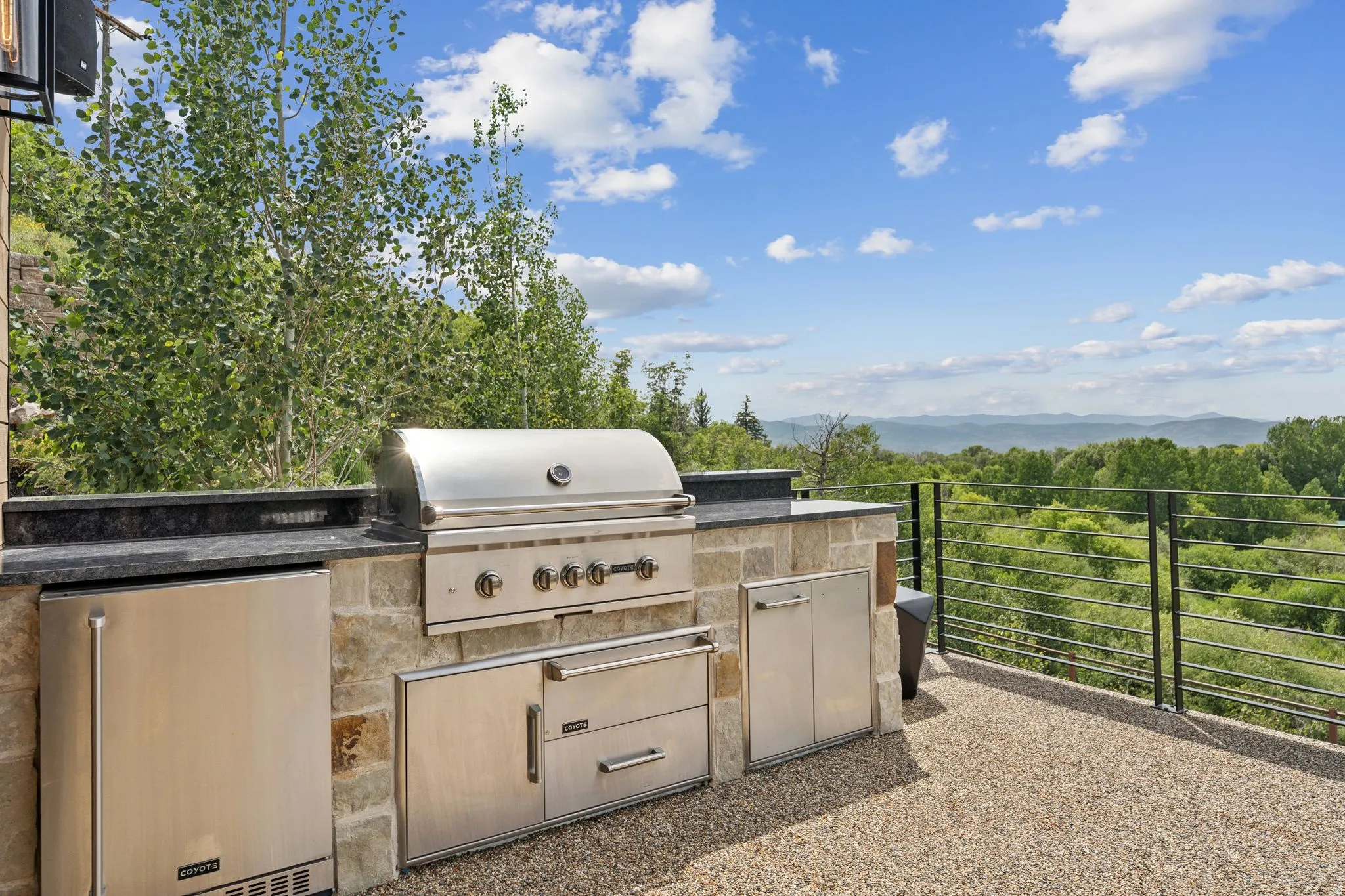 Outdoor kitchen with a stainless steel grill, integrated storage, and an under-counter refrigerator
