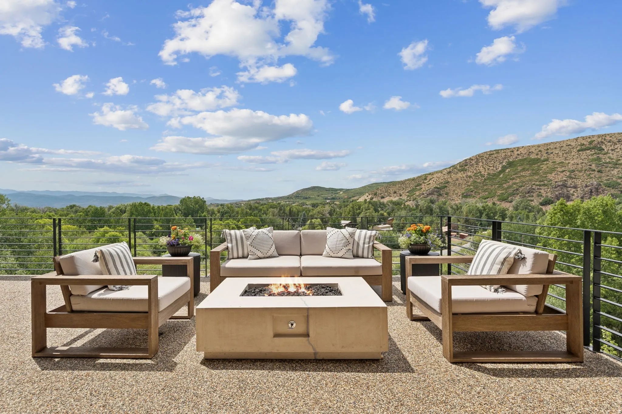 Spacious outdoor patio featuring a fire pit, composite decking, and cable railing