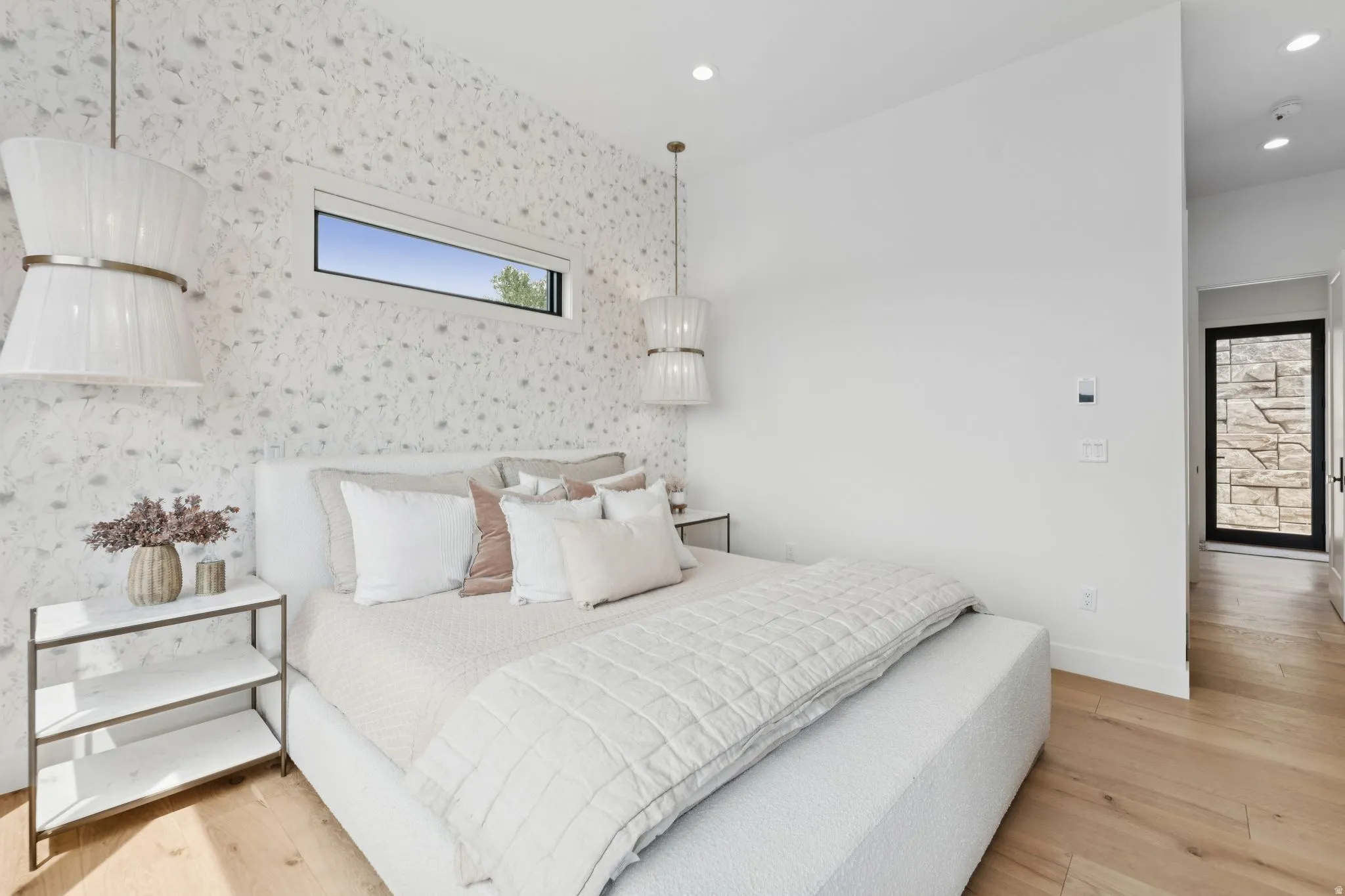 Bedroom featuring a vaulted ceiling with recessed lighting, patterned wallpaper, and light wood-finish flooring