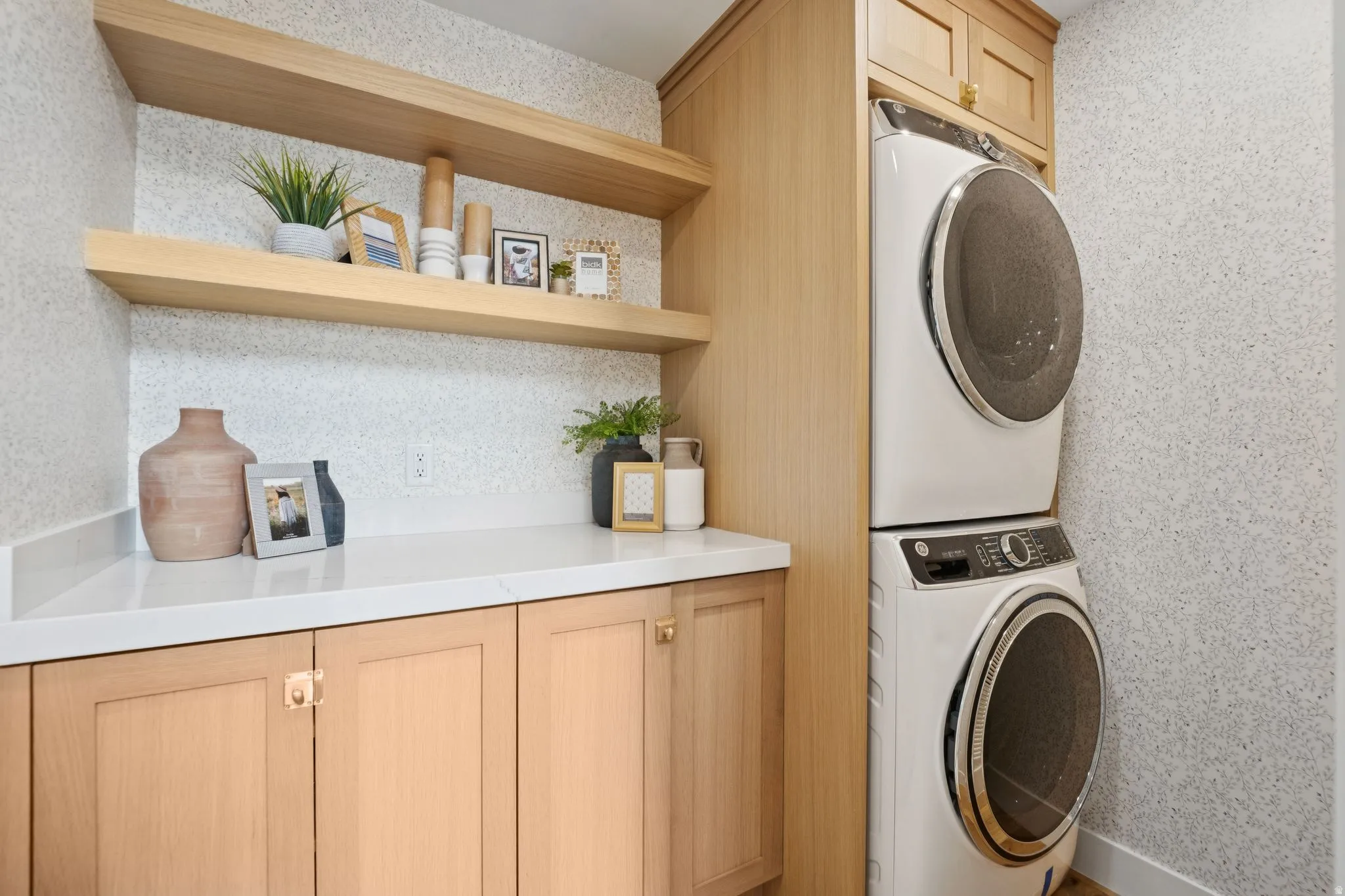 Laundry area featuring light wood cabinetry, white countertops, and open shelving