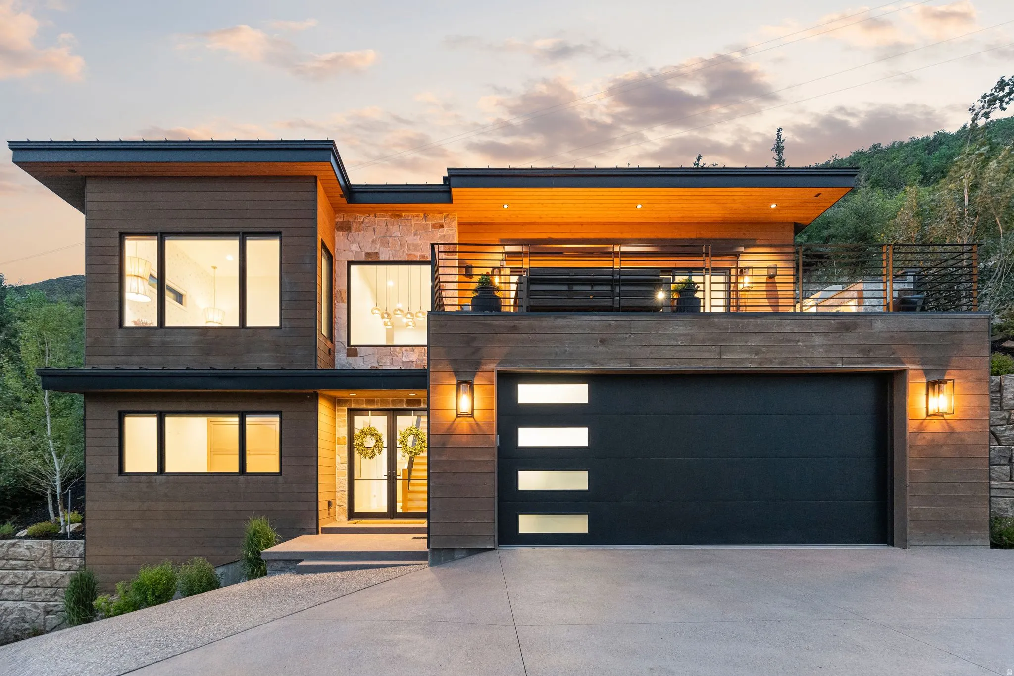 Modern exterior featuring dark wood-finish siding, stone accents, and a flat roofline