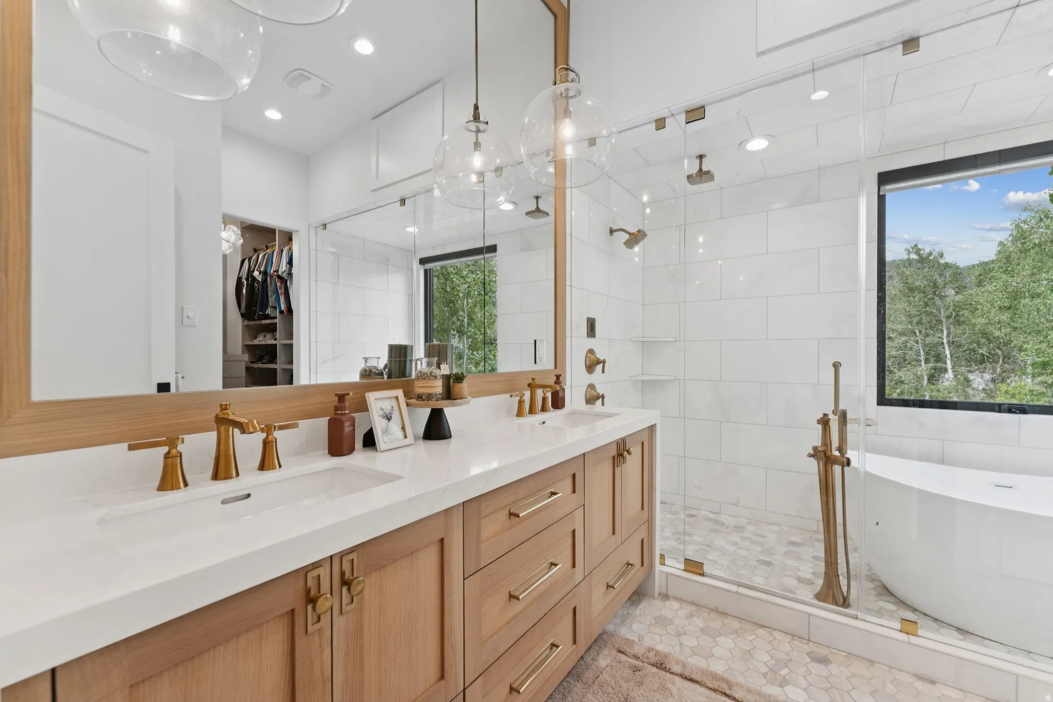 Double vanity featuring light wood-finish cabinetry, white countertops, and brass-tone fixtures