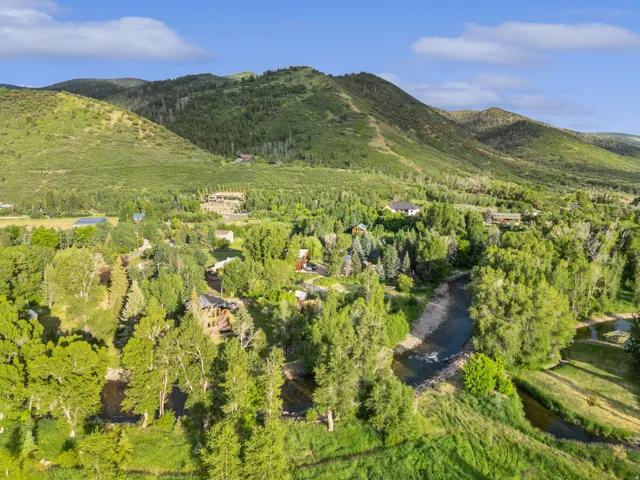 Lush green landscape featuring a river, mature trees, and mountainous terrain