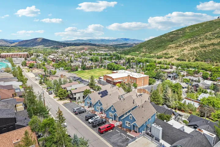 Aerial perspective showcasing a residential area with varied housing styles, surrounding green hills, and distant mountains