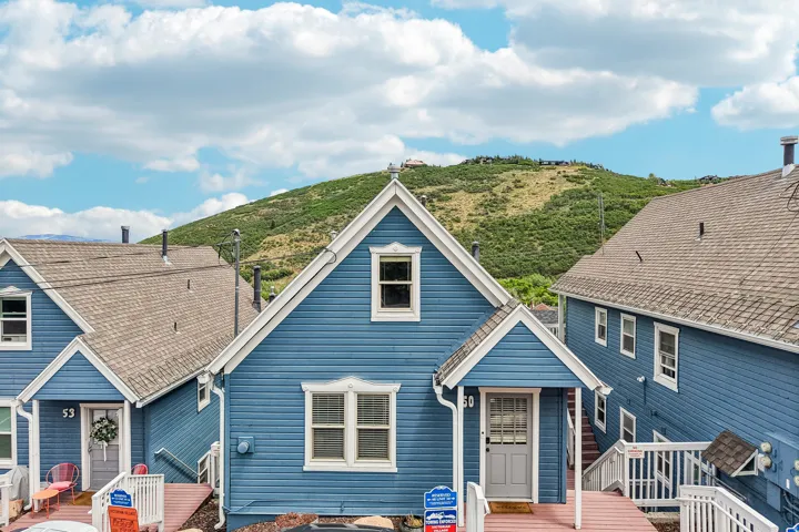 Blue siding property featuring white trim, a gabled roofline, a front porch with an awning, and a prominent mountain backdrop
