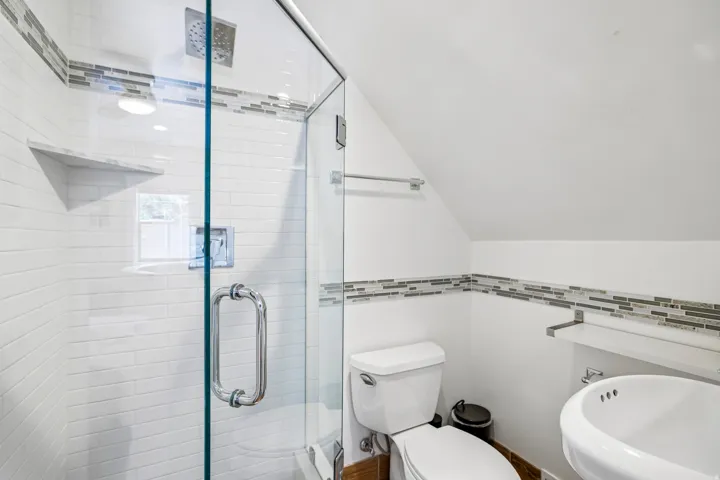 Contemporary bathroom featuring a glass-enclosed shower with subway tile surround and a built-in shelf
