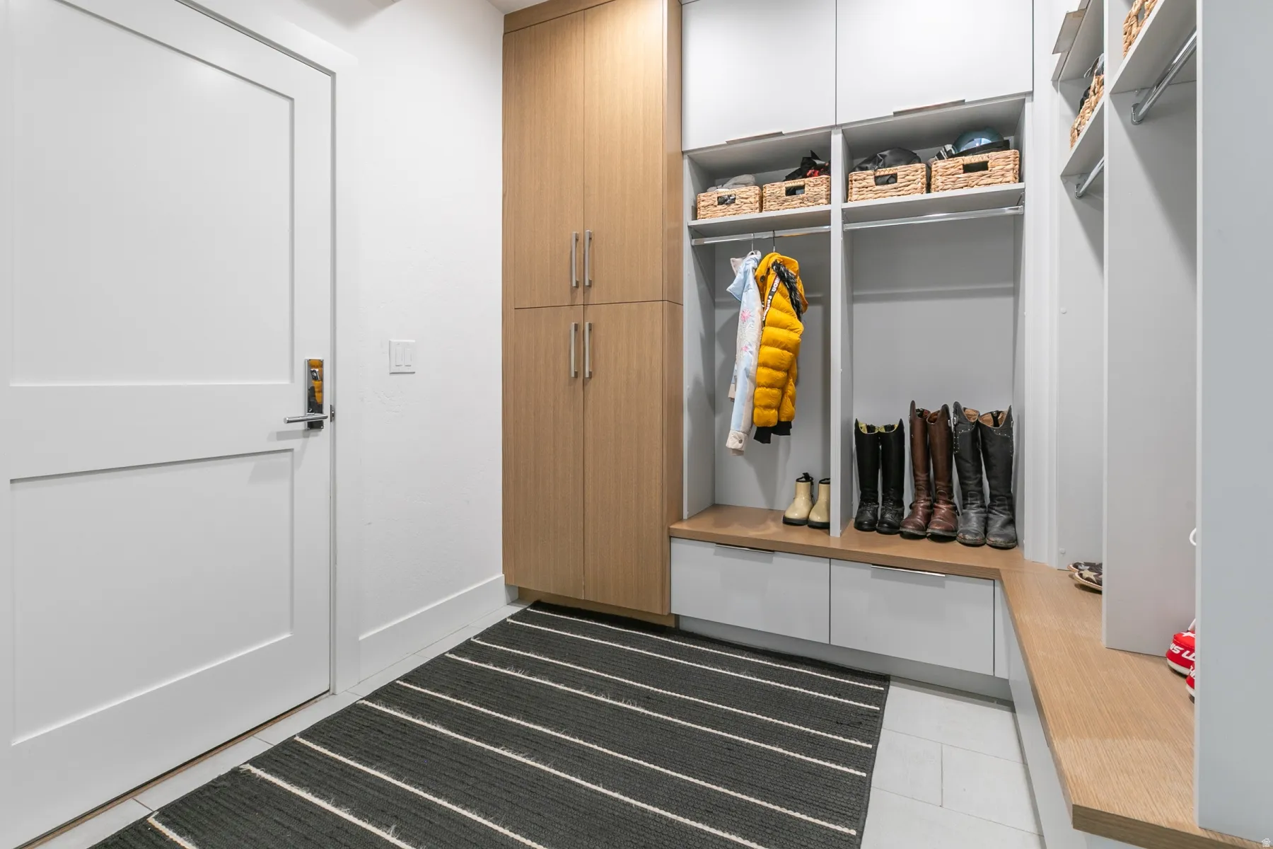Entryway featuring built-in storage with light wood-finish cabinetry, white paneled doors, and light gray modular shelving