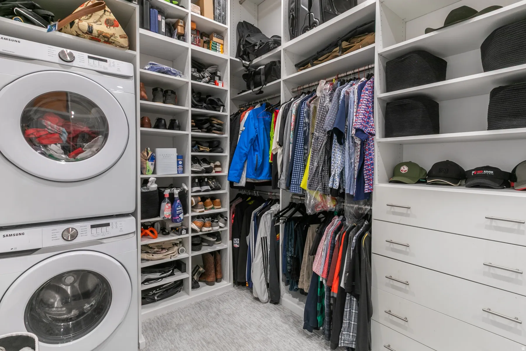 Custom closet system featuring a stacked washer and dryer, extensive shelving, hanging rods, and integrated drawers