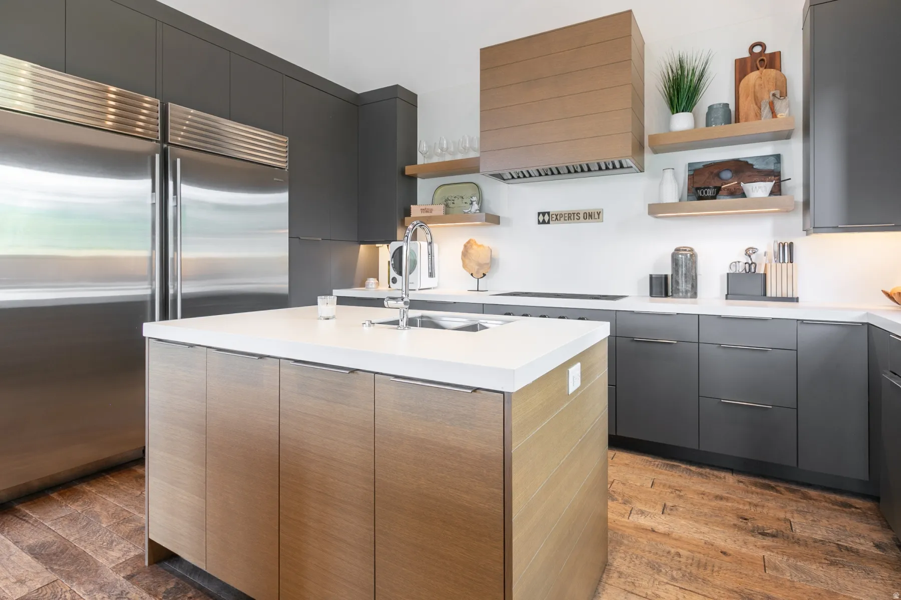 Modern kitchen featuring a central island with a built-in sink and light wood-finish cabinetry