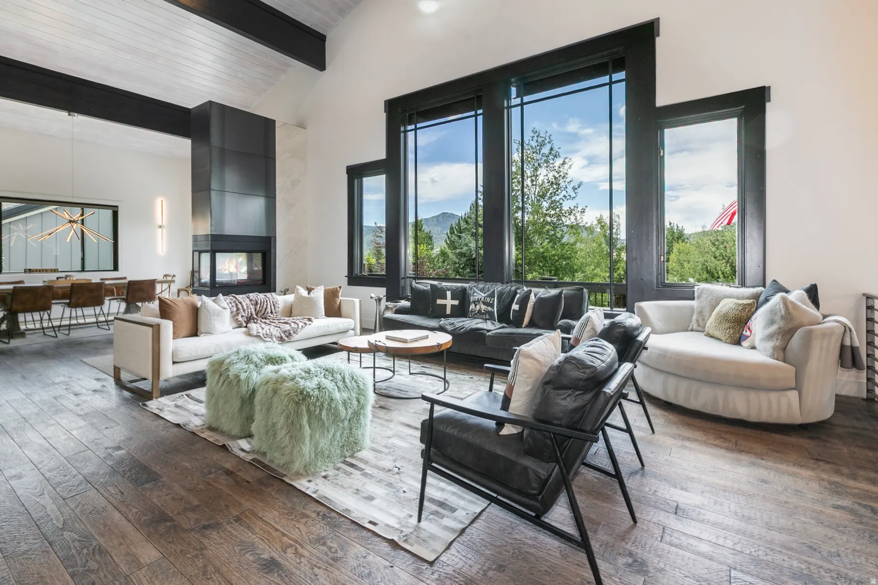 Spacious living area featuring high vaulted ceilings with exposed dark beams and wood-finish flooring