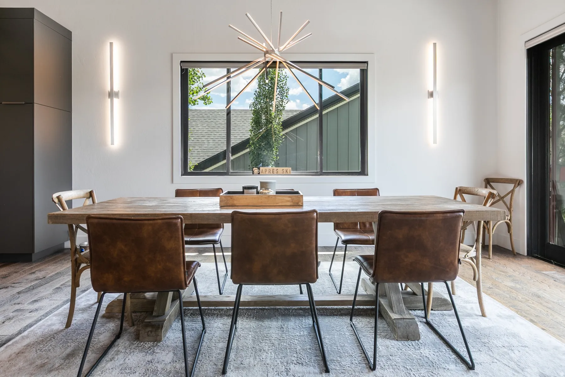 Dining area featuring abundant natural light, a contemporary sputnik chandelier, two vertical wall sconces, dark frame windows, and wood-finish flooring