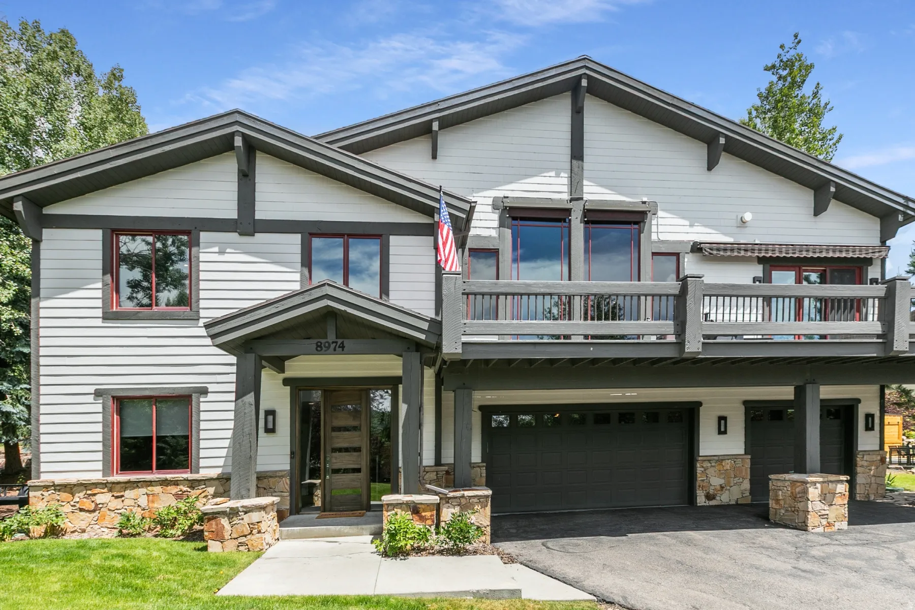 Multi-level exterior featuring white siding with dark trim accents, a stone foundation, and a two-car garage