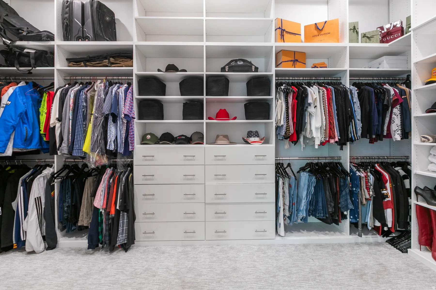 Custom built-in closet system featuring white shelving, multiple hanging rods, and integrated drawer units