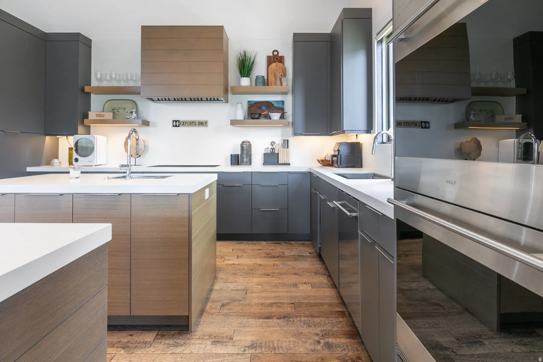 Modern kitchen featuring wood-finish flooring, dark gray cabinetry, and white countertops