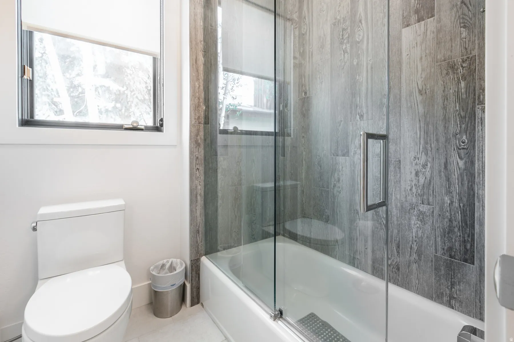 Bathroom featuring a full-size bathtub with a glass shower enclosure and wood-finish wall paneling