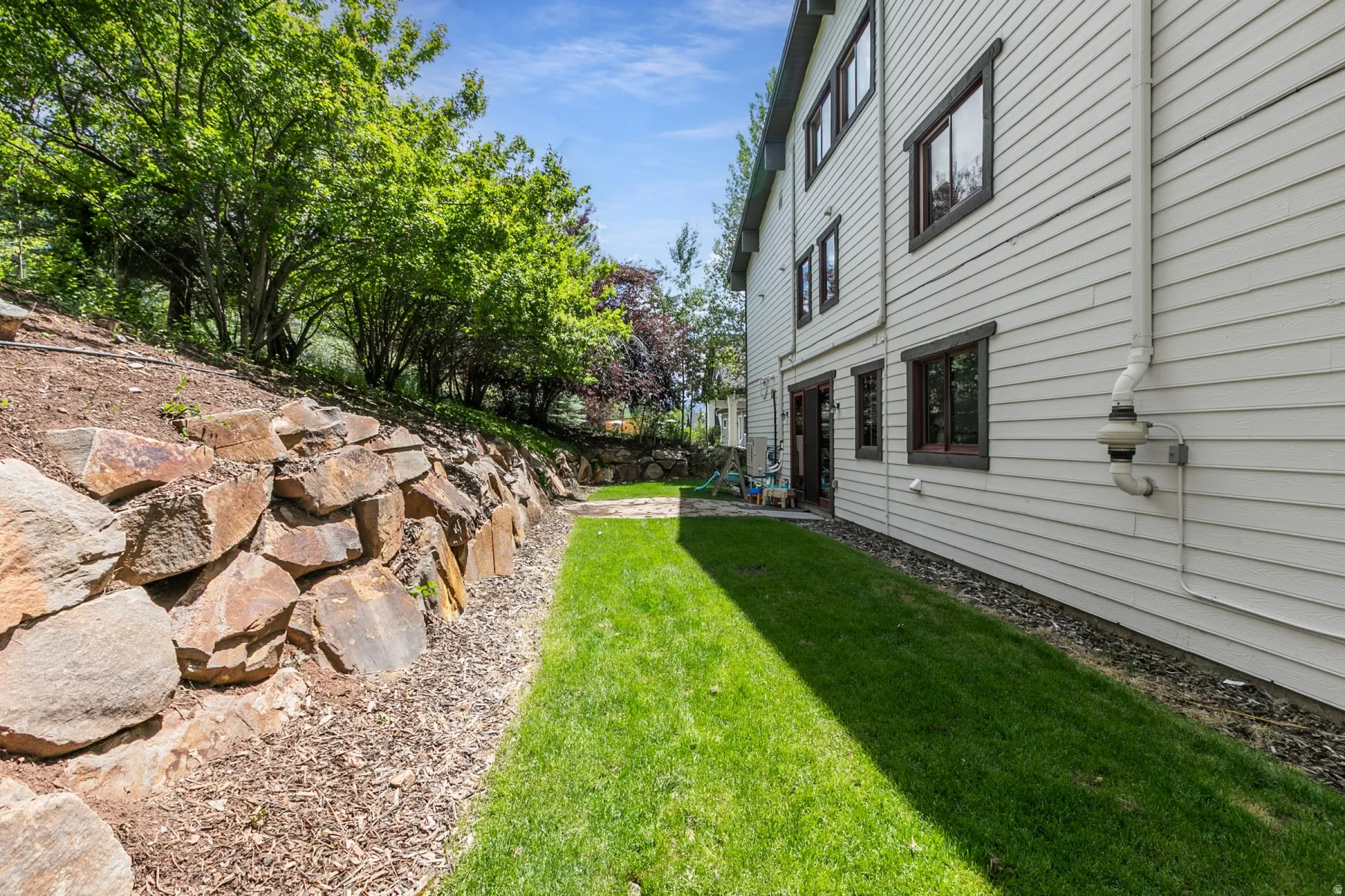 Manicured lawn borders a stacked stone retaining wall