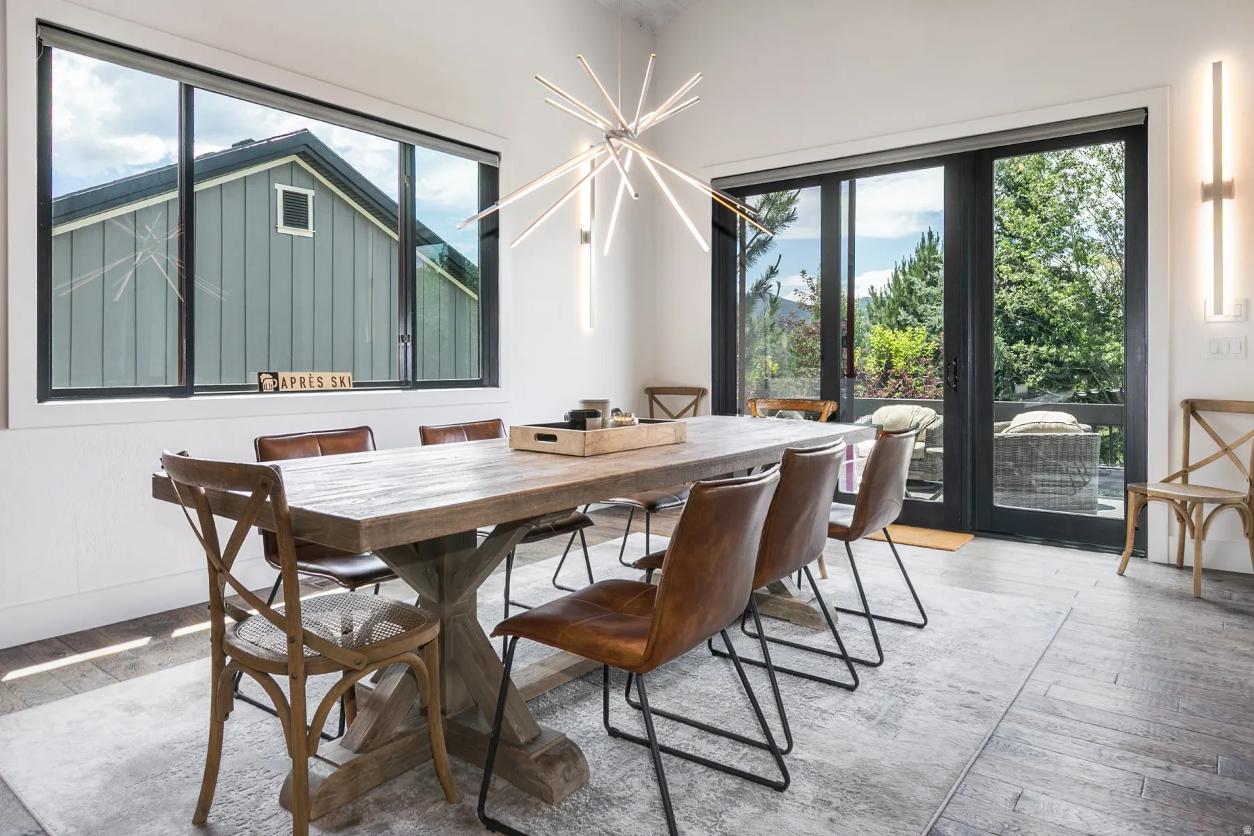 Spacious dining area featuring dark-framed glass doors, a large picture window, and a contemporary chandelier