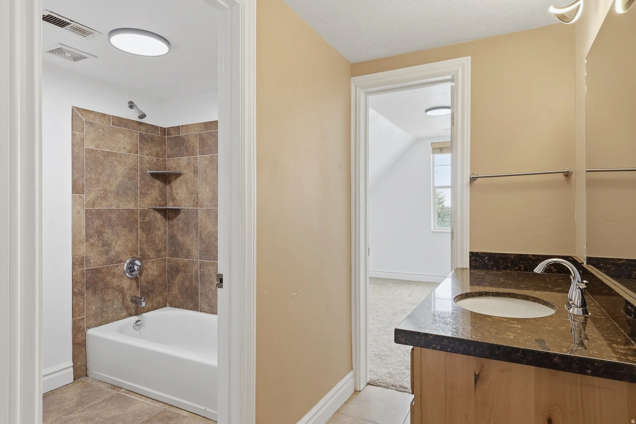 Bathroom featuring a tub/shower combination with tile surround and integrated corner shelving