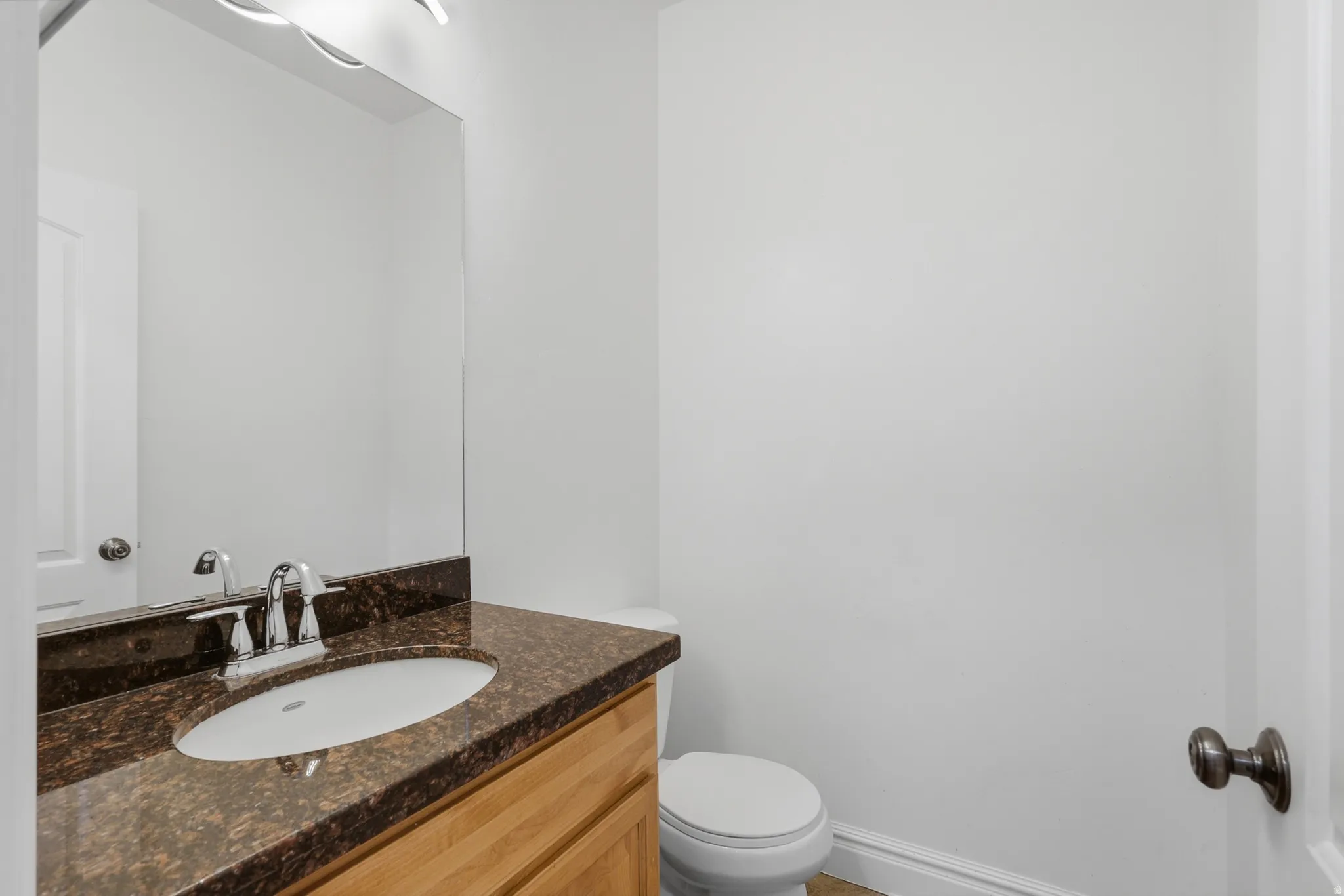 Bathroom featuring a wood-finish vanity with a brown speckled countertop, an undermount sink, and a chrome faucet