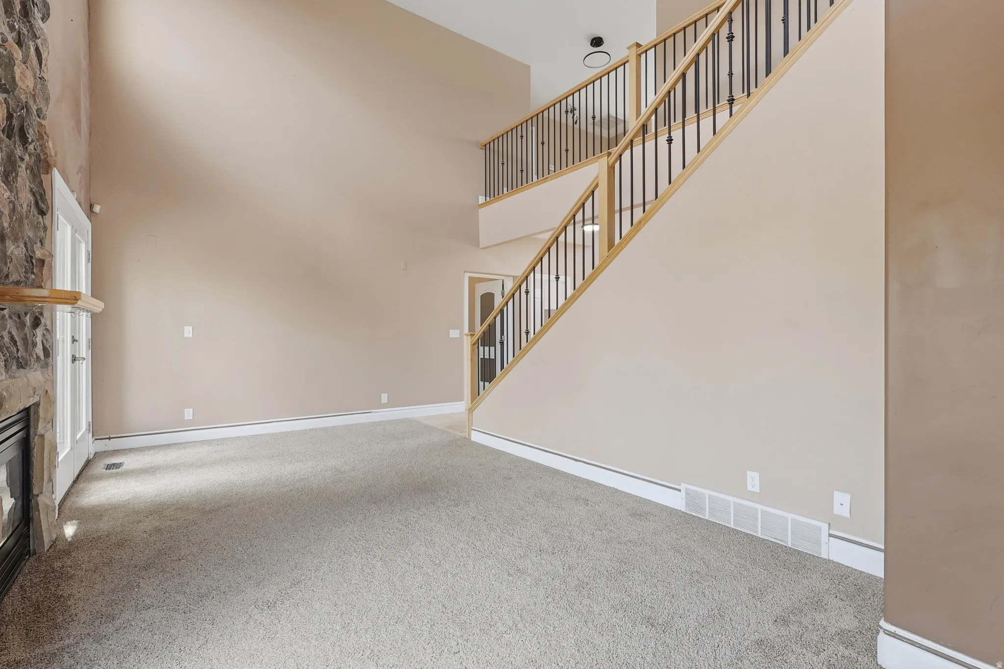 Two-story entryway with a vaulted ceiling and an open staircase featuring wood handrails and black metal balusters