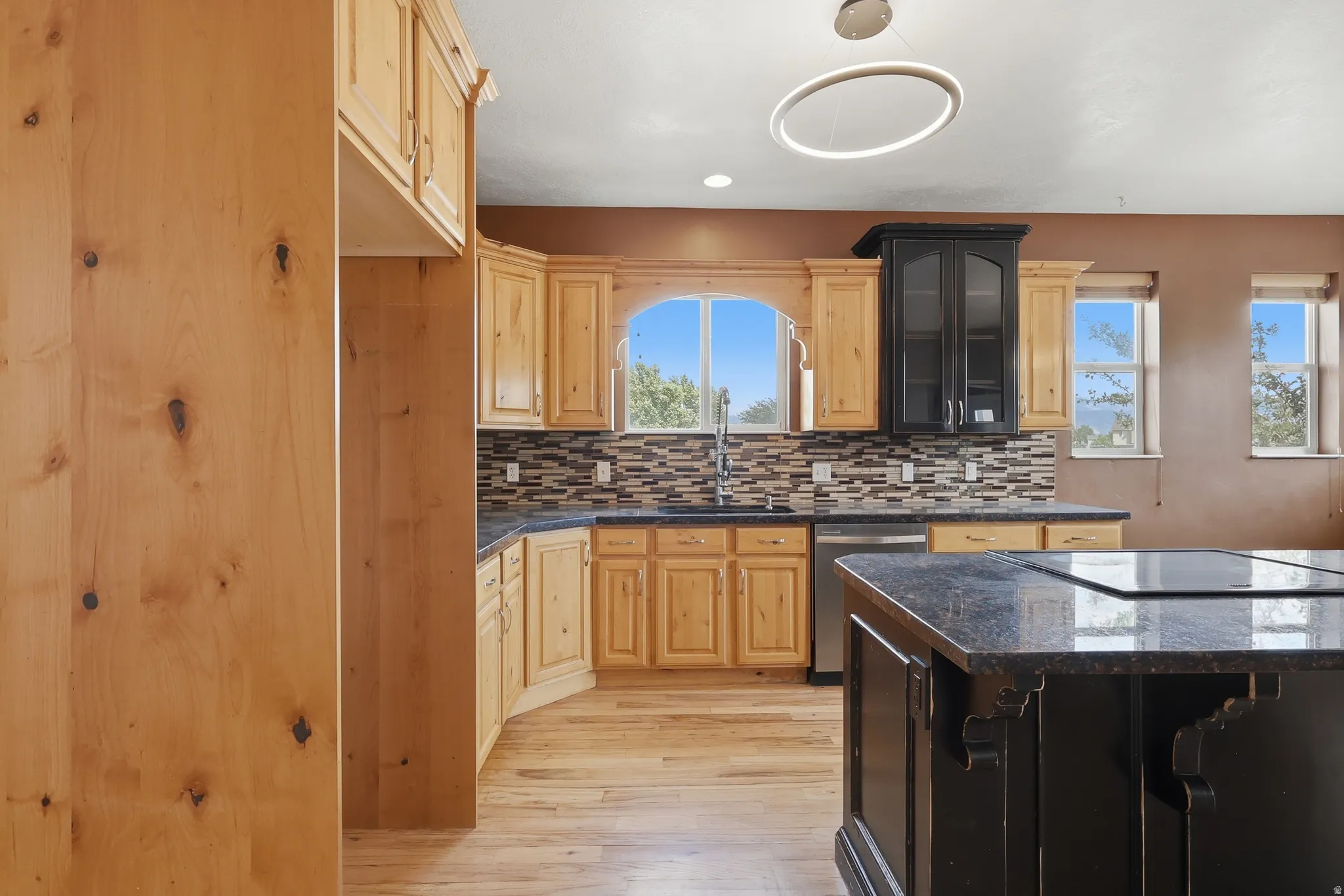 Kitchen featuring light wood cabinetry and a dark granite-style island