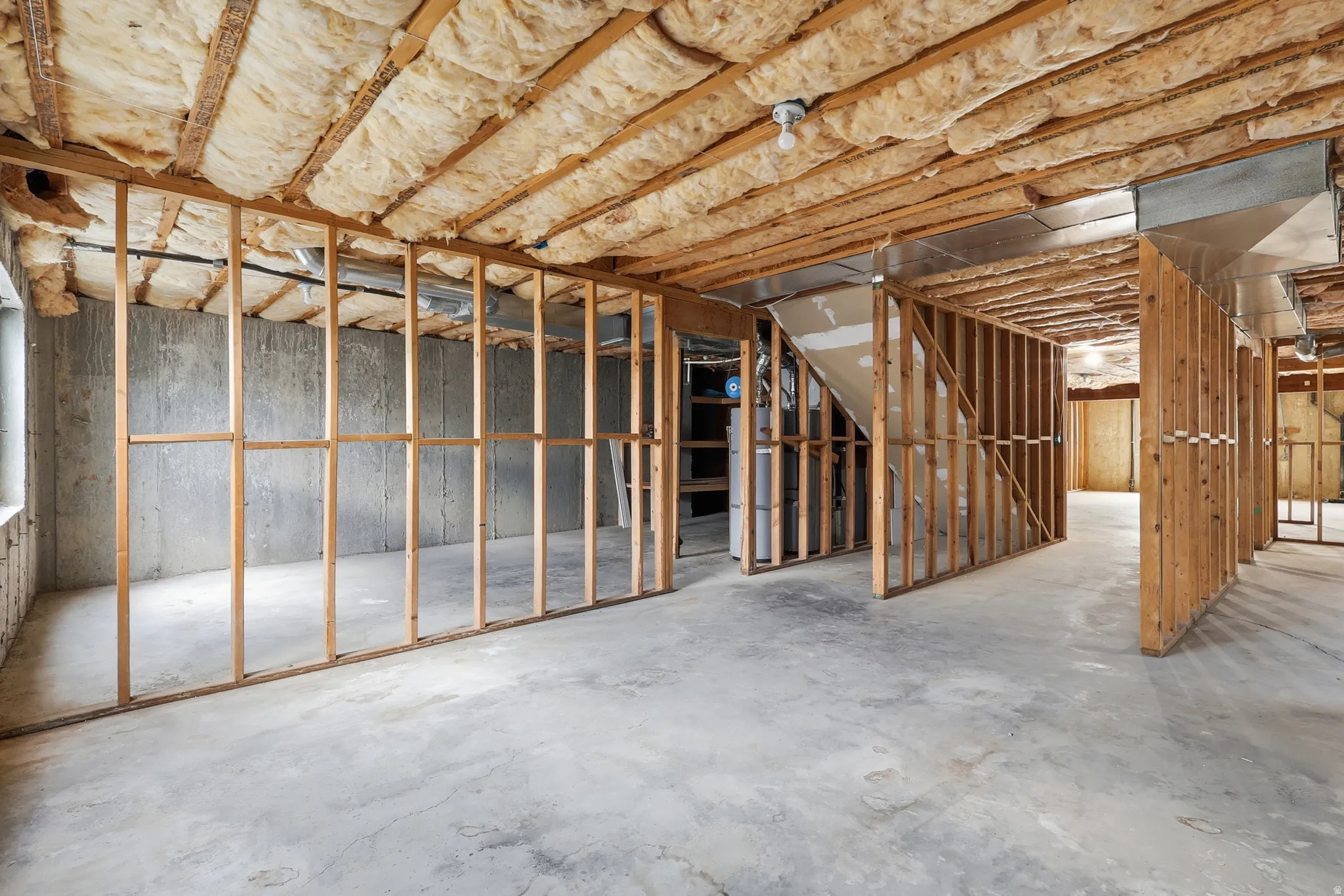 Unfinished basement featuring concrete flooring, exposed wooden framing, visible insulation in the ceiling, and concrete foundation walls