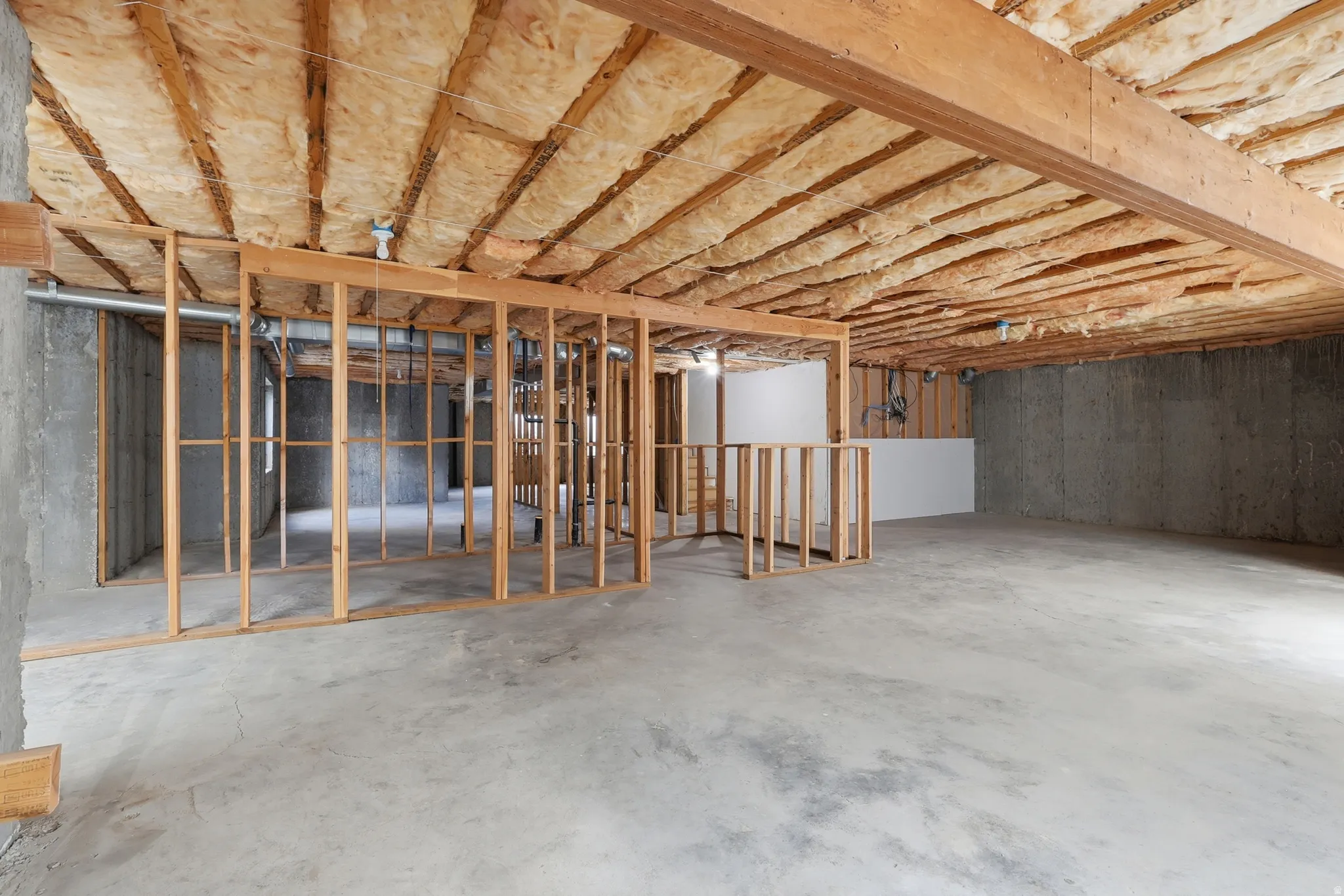 Unfinished basement featuring concrete flooring and exposed wood framing