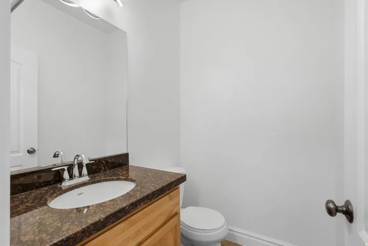 Bathroom featuring a wood-finish vanity with a brown speckled countertop, an undermount sink, and a chrome faucet