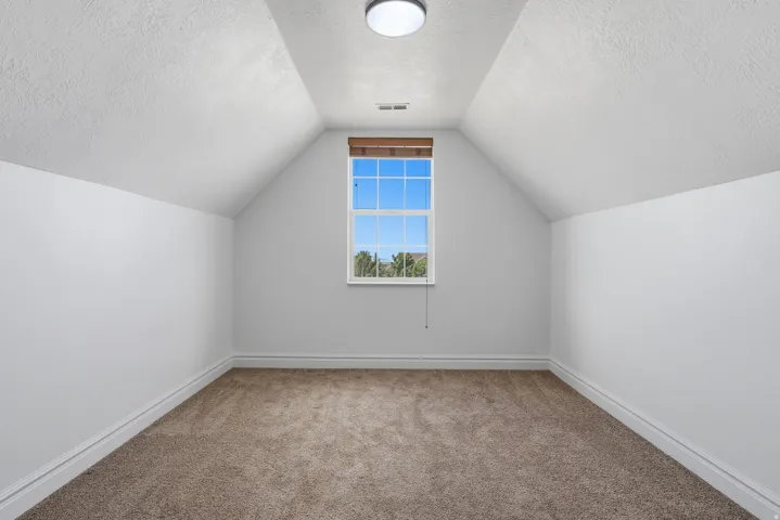 Carpeted room with a pitched ceiling and a single window