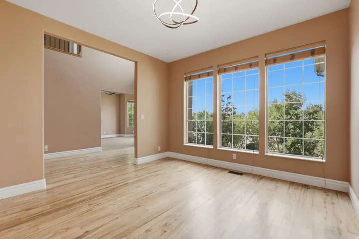 Bright living space featuring three large windows, wood-finish flooring, and a contemporary light fixture