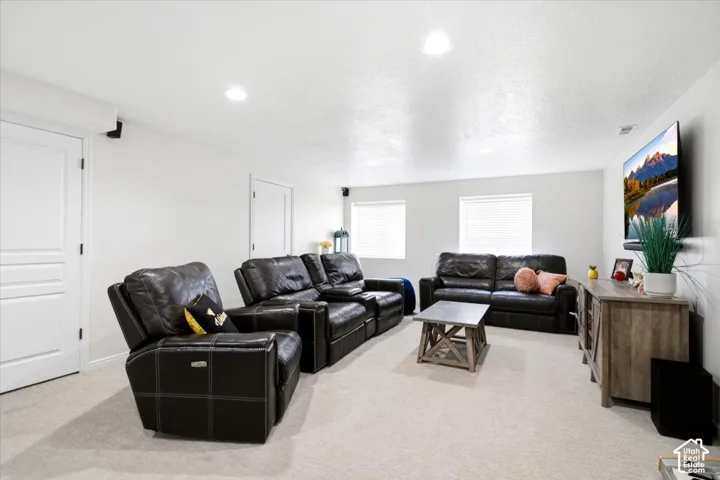 Spacious entertainment area featuring light-toned carpeting and recessed ceiling lighting