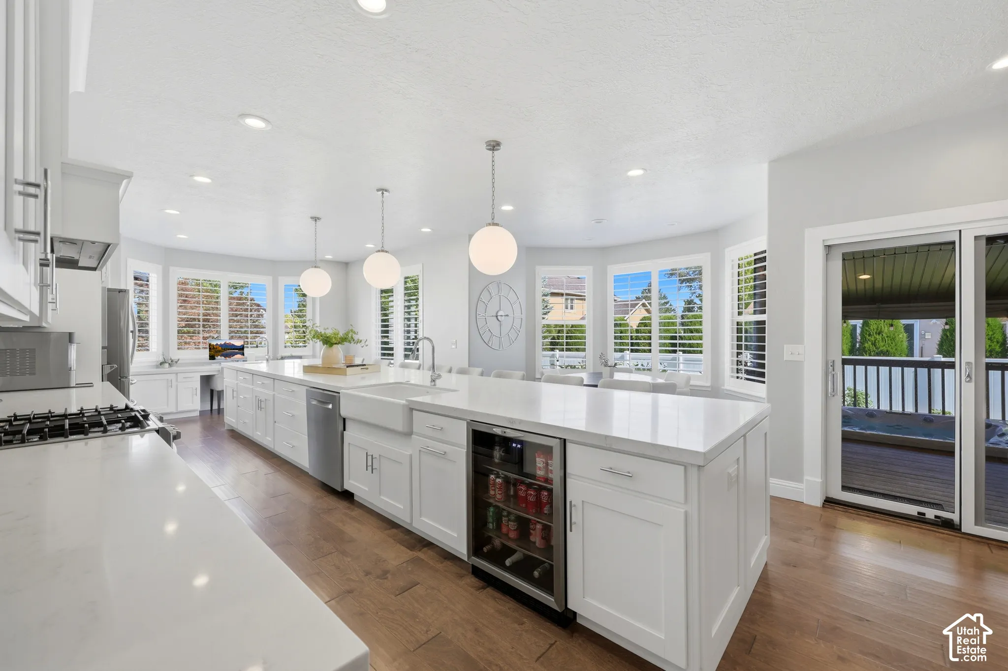 Bright kitchen featuring an expansive island with white countertops, a built-in beverage cooler, and an integrated farmhouse sink