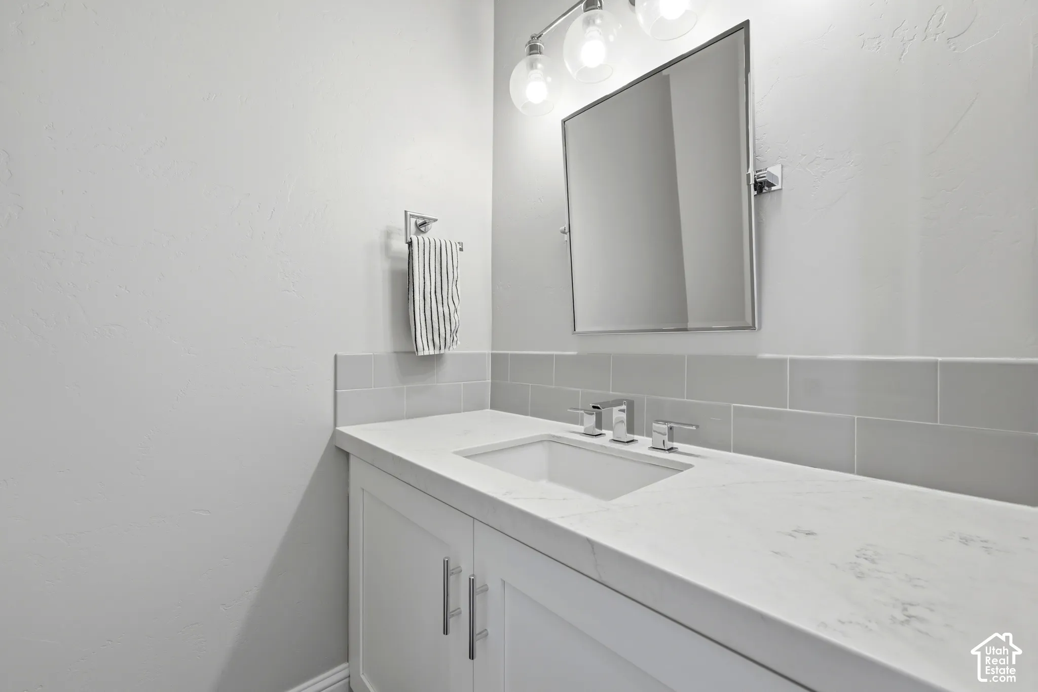 Bathroom vanity featuring a white countertop with integrated sink, chrome faucet, and rectangular mirror