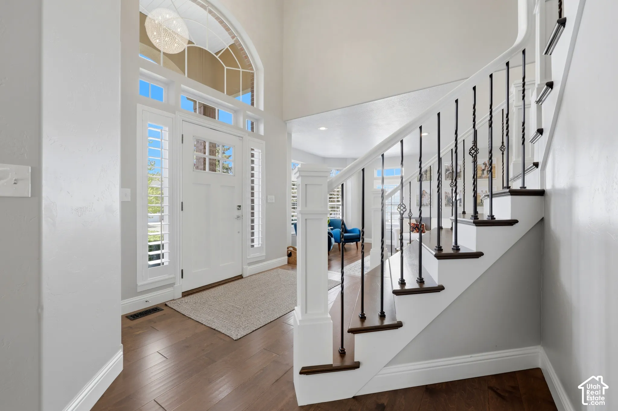 Grand entry featuring wood-finish flooring, a white front door with sidelights, and an arched transom window