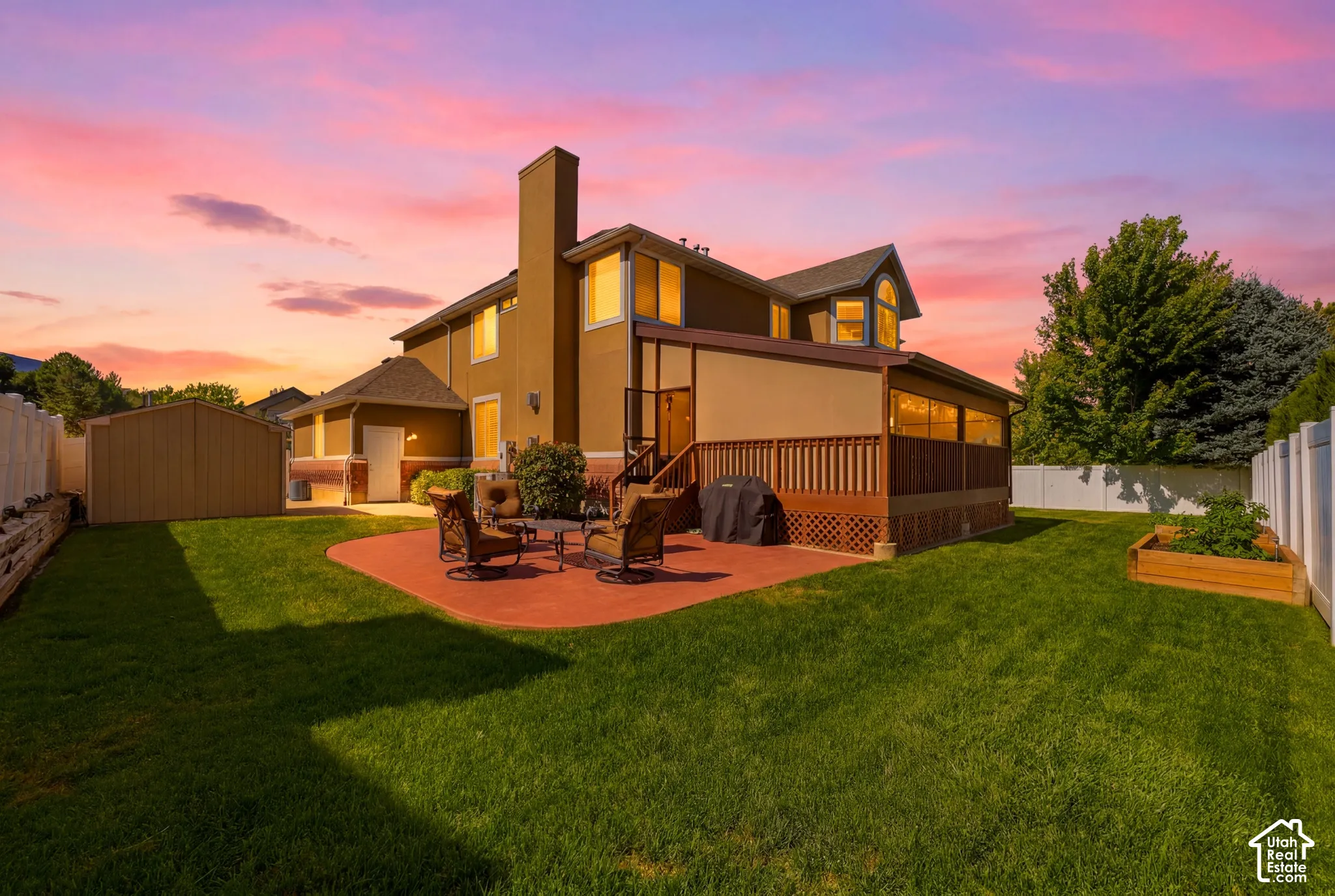 Spacious backyard with a large deck, concrete patio, and mature landscaping