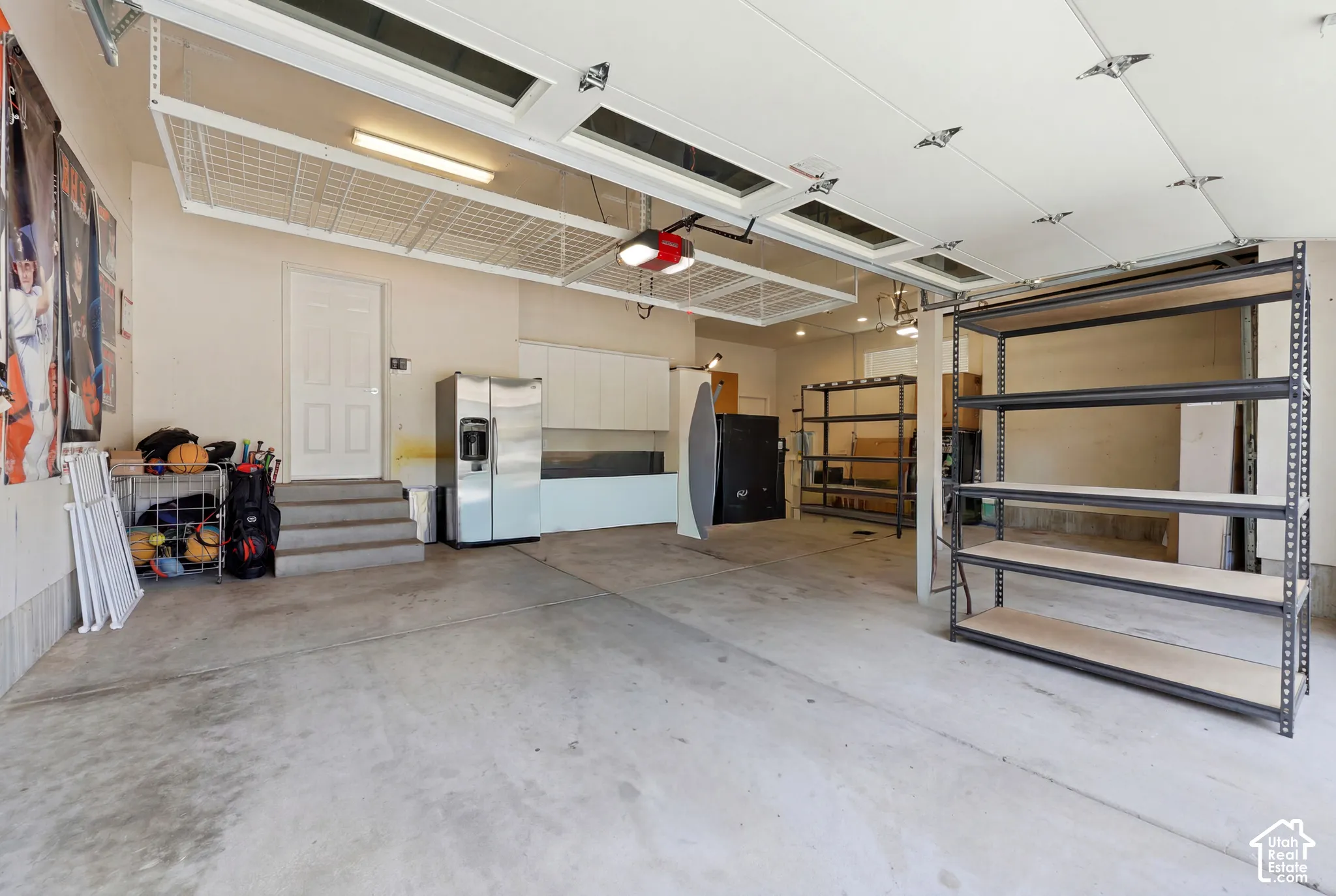 Spacious garage featuring concrete flooring, overhead storage racks, fluorescent lighting, and built-in shelving units