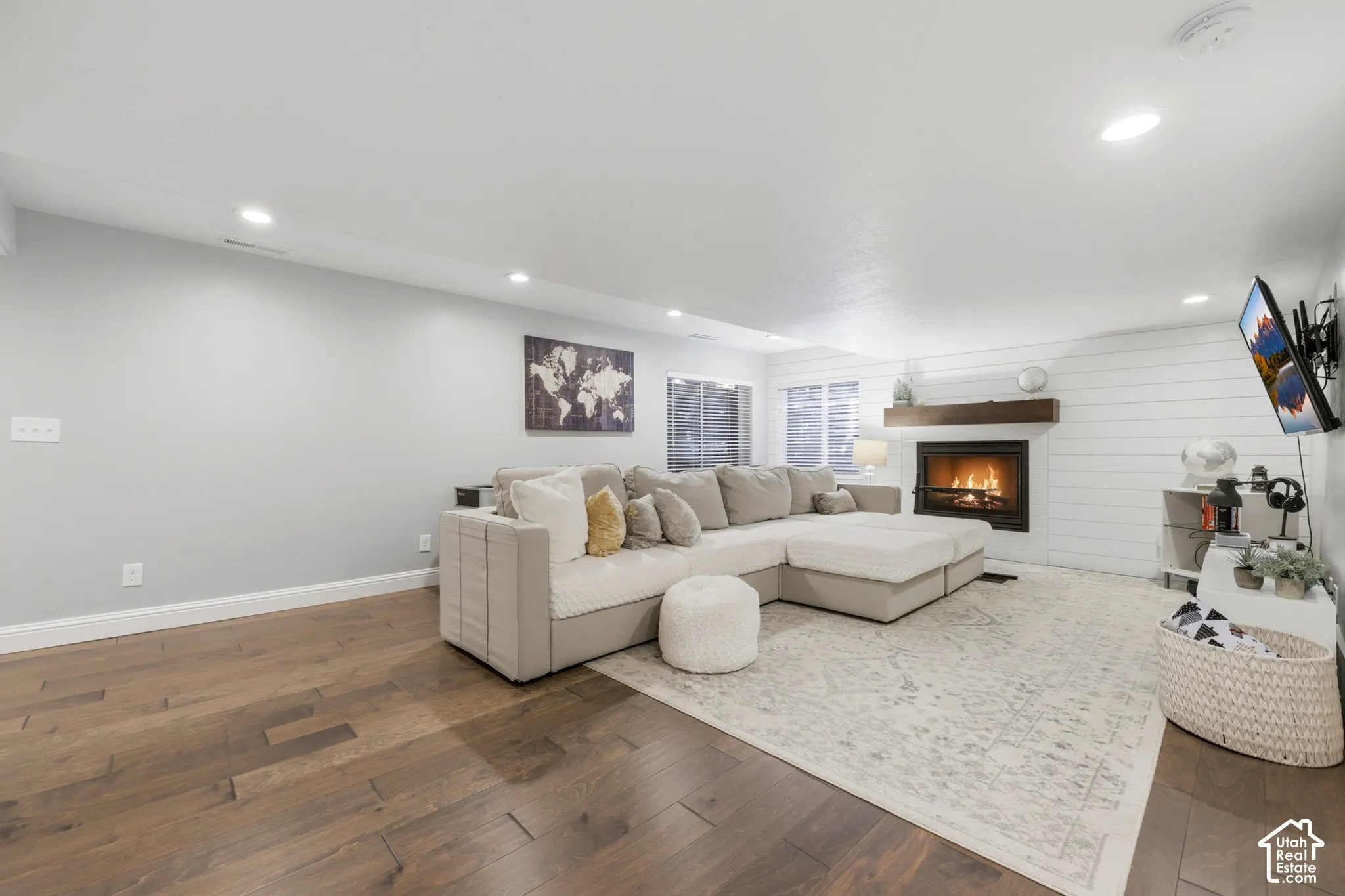 Living area featuring wood-finish flooring, recessed lighting, and a fireplace with a wood mantle and shiplap surround