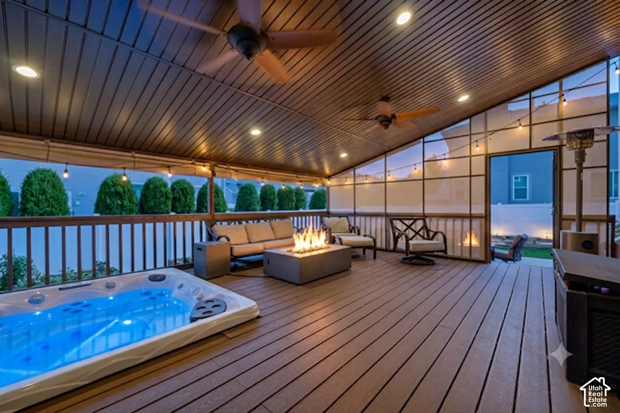Expansive deck featuring composite flooring, a built-in hot tub, and a covered patio with recessed lighting and ceiling fans