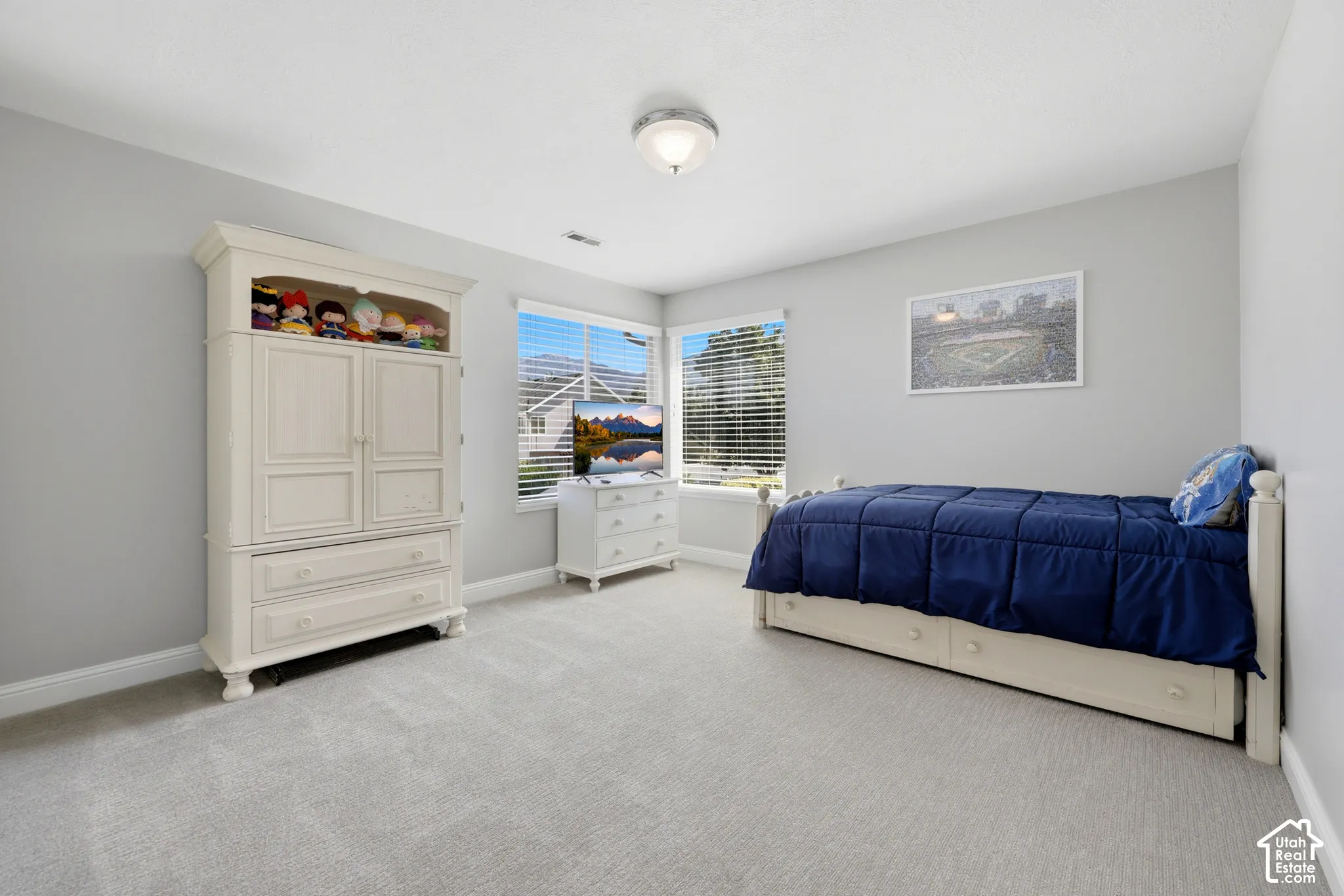Carpeted room featuring light gray walls, a ceiling-mounted light fixture, and multiple windows with blinds
