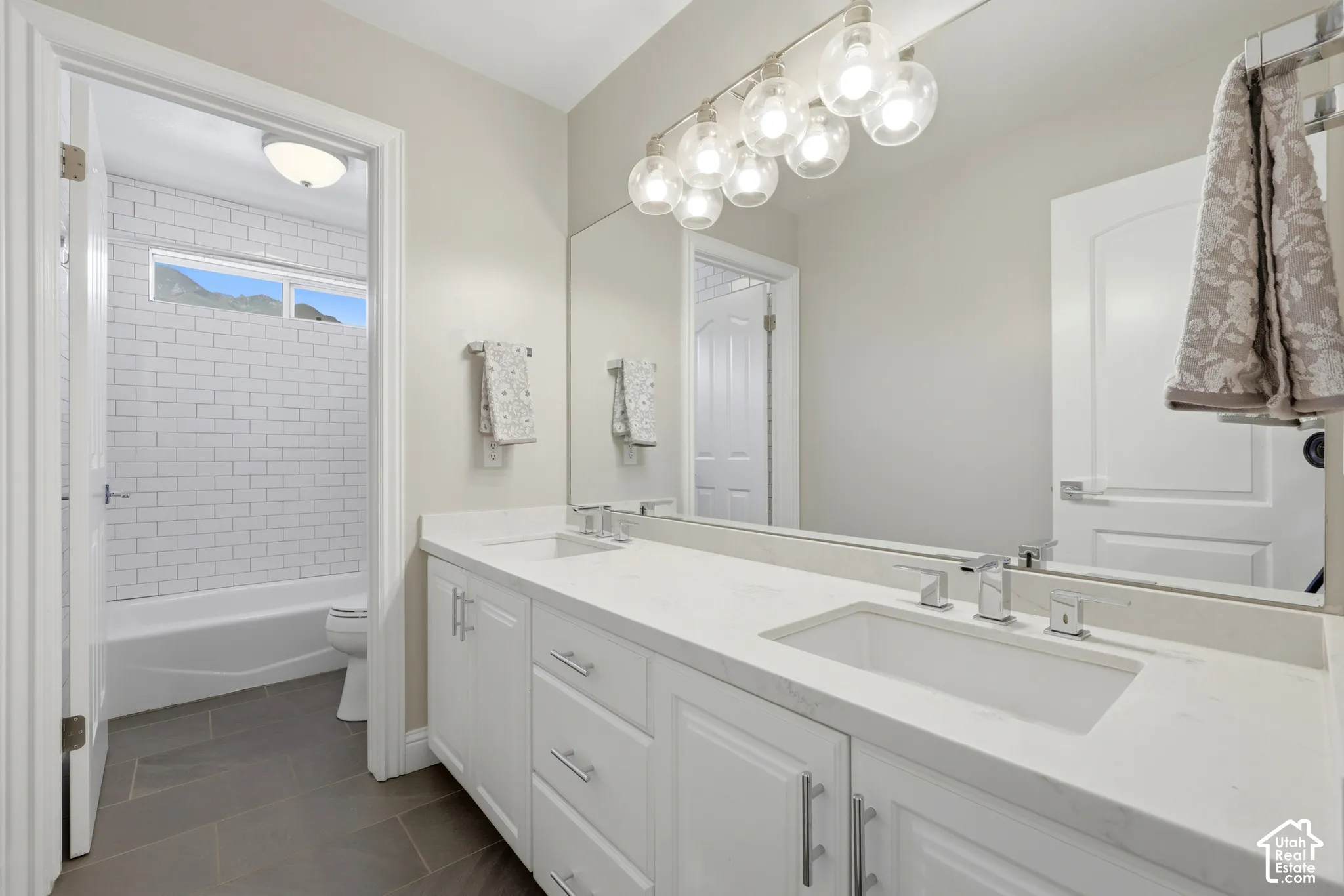 Bathroom featuring a double vanity with white cabinetry, integrated sinks, and chrome fixtures